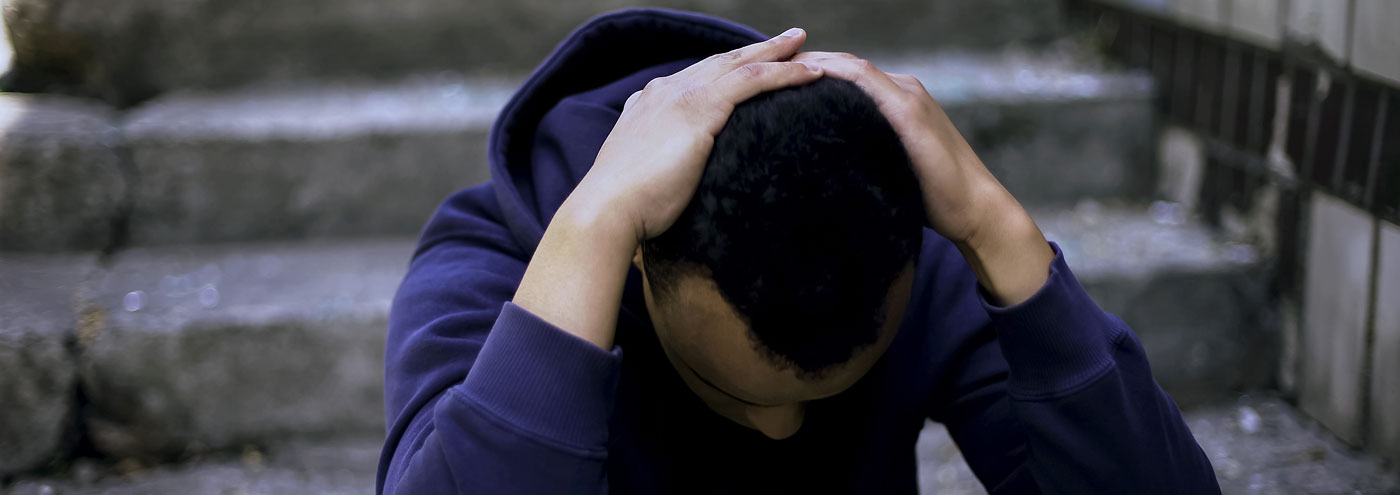 Teenager with head in hands on steps